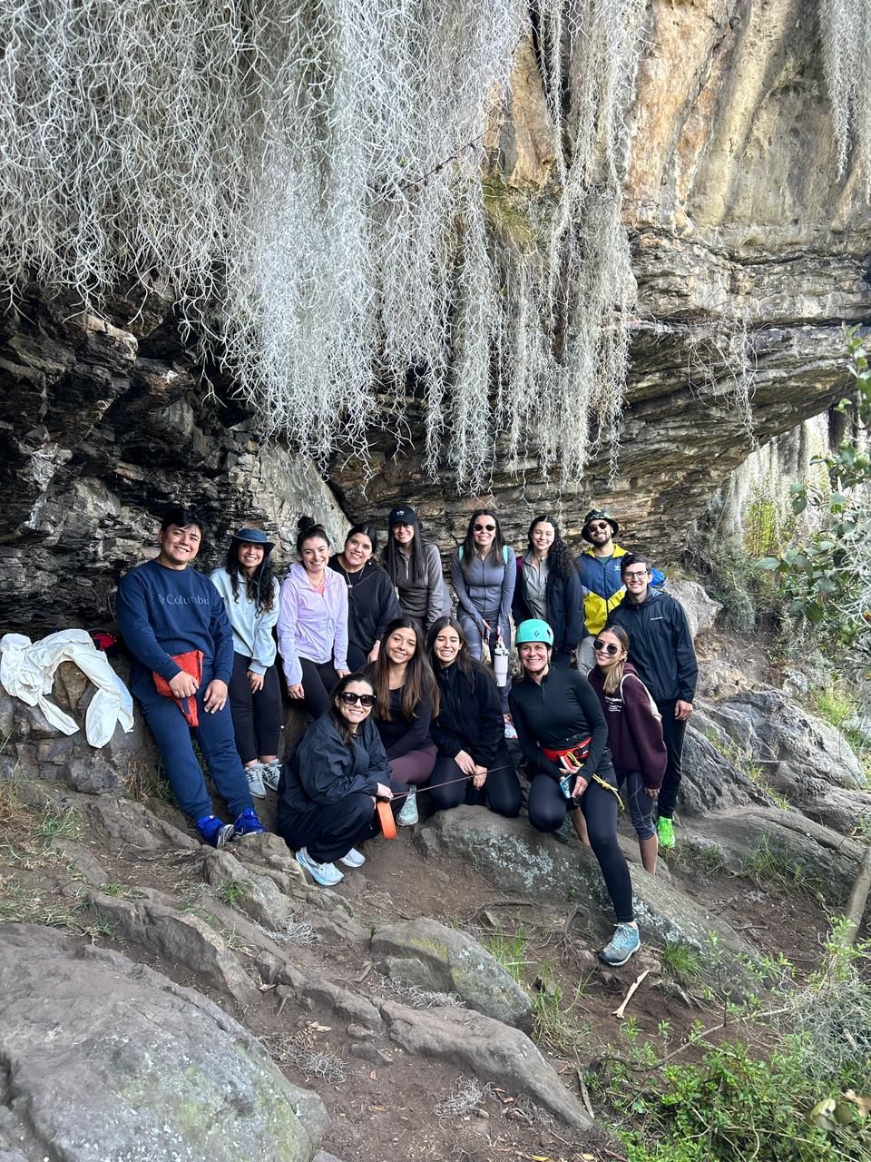 Grupo grande reunido bajo la roca con musgo colgante